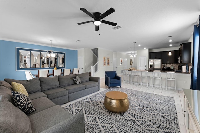 living room with ceiling fan with notable chandelier, crown molding, sink, and light tile patterned floors