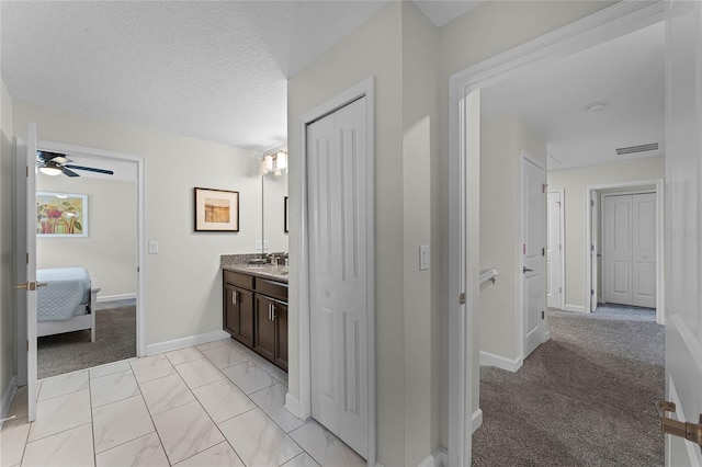 bathroom featuring ceiling fan, vanity, and a textured ceiling