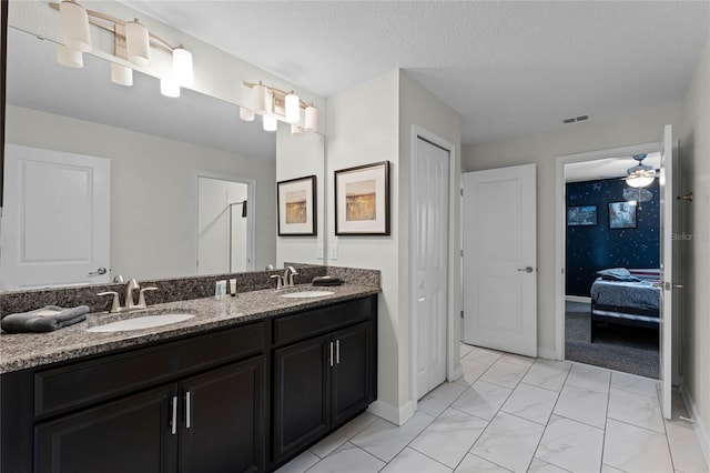 bathroom featuring ceiling fan, vanity, and a textured ceiling