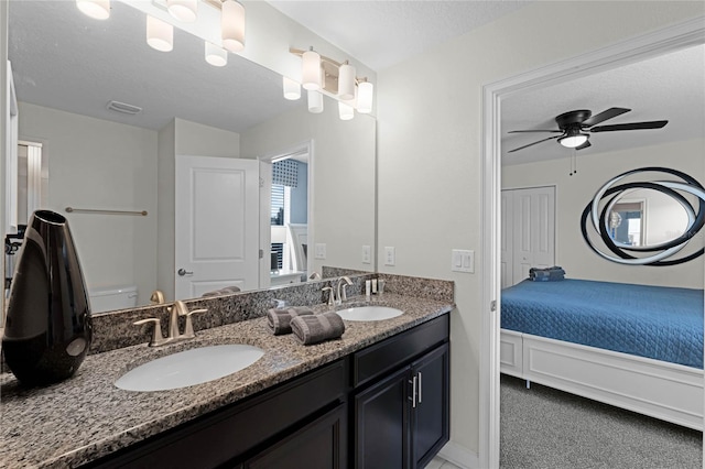 bathroom featuring a textured ceiling, ceiling fan, vanity, and toilet