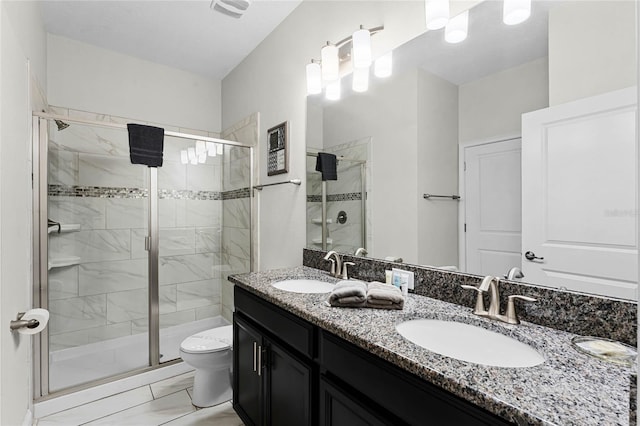 bathroom featuring a shower with shower door, vanity, and toilet