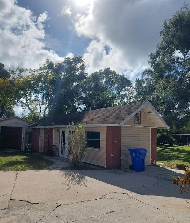 single story home with french doors, an outdoor structure, and a front lawn