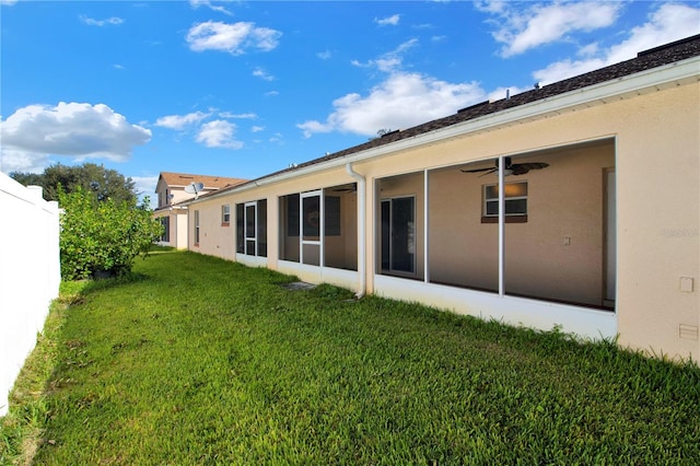 rear view of property featuring ceiling fan and a lawn