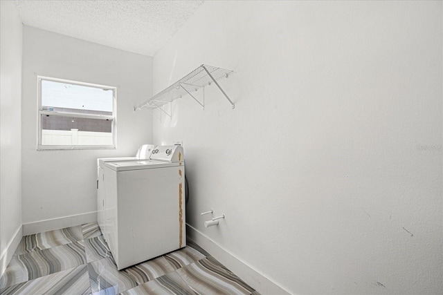 clothes washing area with a textured ceiling and washing machine and dryer