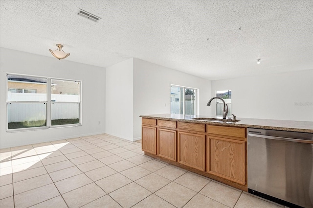 kitchen featuring sink, light tile patterned flooring, stainless steel dishwasher, and a textured ceiling