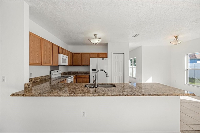 kitchen featuring sink, white appliances, kitchen peninsula, and a wealth of natural light