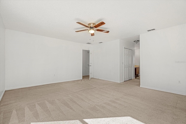 unfurnished room featuring ceiling fan, light colored carpet, and a textured ceiling