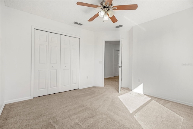 unfurnished bedroom with light colored carpet, a closet, and ceiling fan