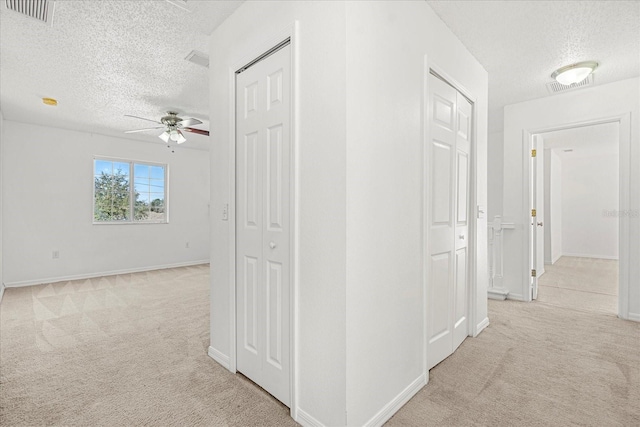 hall featuring a textured ceiling and light carpet