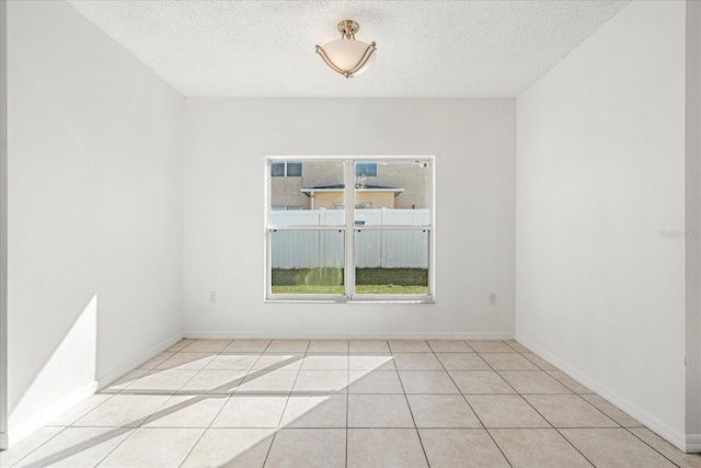 unfurnished room featuring a textured ceiling and light tile patterned floors