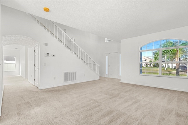 unfurnished living room with light colored carpet and a textured ceiling