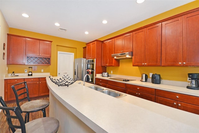 kitchen with stainless steel appliances, hardwood / wood-style flooring, sink, and a kitchen breakfast bar