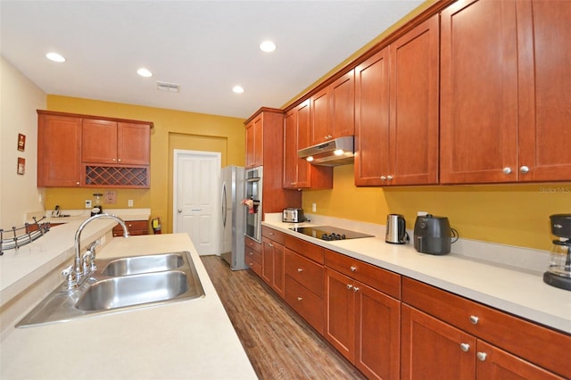 kitchen featuring wood-type flooring, black electric cooktop, stainless steel fridge, and sink