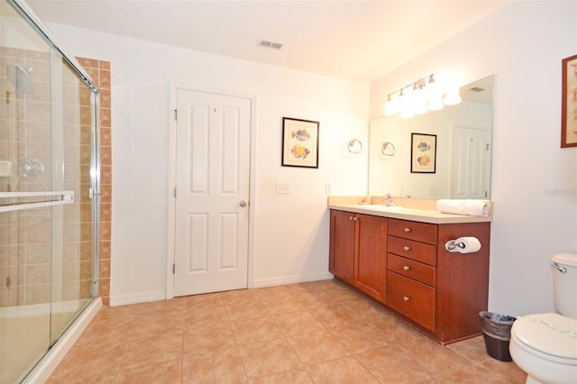 bathroom featuring tile patterned flooring, a shower with door, vanity, and toilet