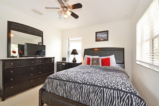 bedroom featuring ceiling fan, multiple windows, and light carpet