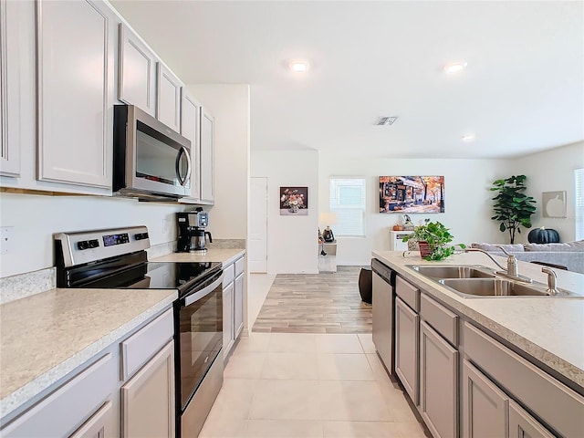 kitchen with sink, appliances with stainless steel finishes, and light hardwood / wood-style flooring