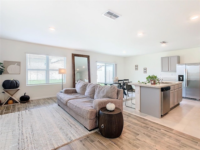 living room with a healthy amount of sunlight, sink, and light wood-type flooring