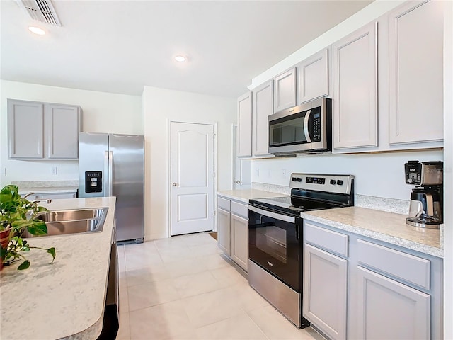 kitchen featuring gray cabinets, stainless steel appliances, sink, and light tile patterned floors