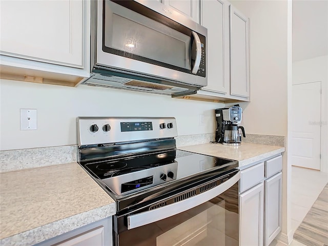 kitchen with light hardwood / wood-style flooring, stainless steel appliances, and white cabinetry