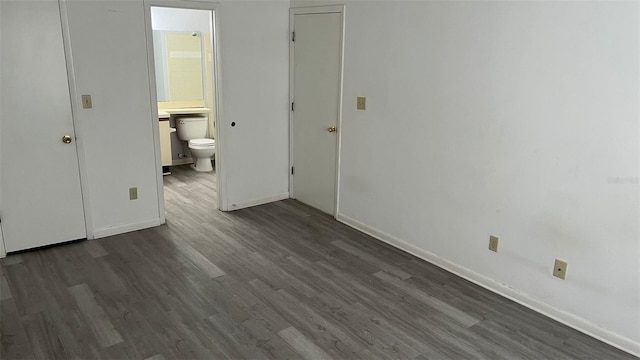 unfurnished bedroom with dark wood-type flooring and connected bathroom