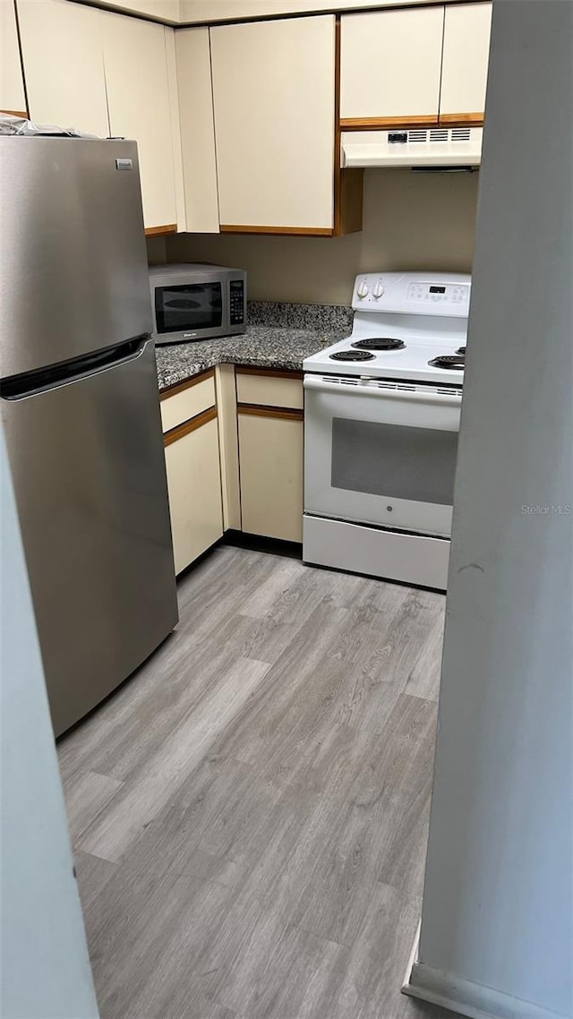 kitchen with appliances with stainless steel finishes, cream cabinetry, and light hardwood / wood-style floors