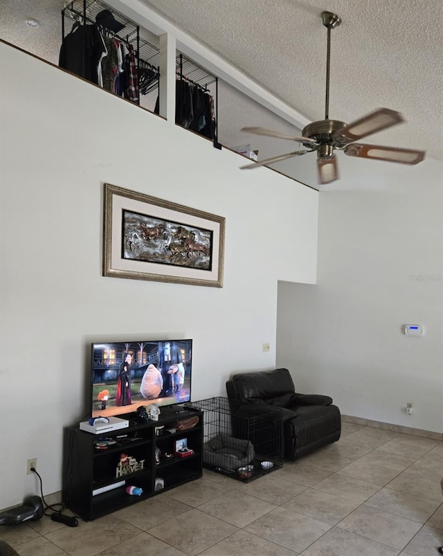 living room featuring ceiling fan, tile patterned flooring, and a textured ceiling