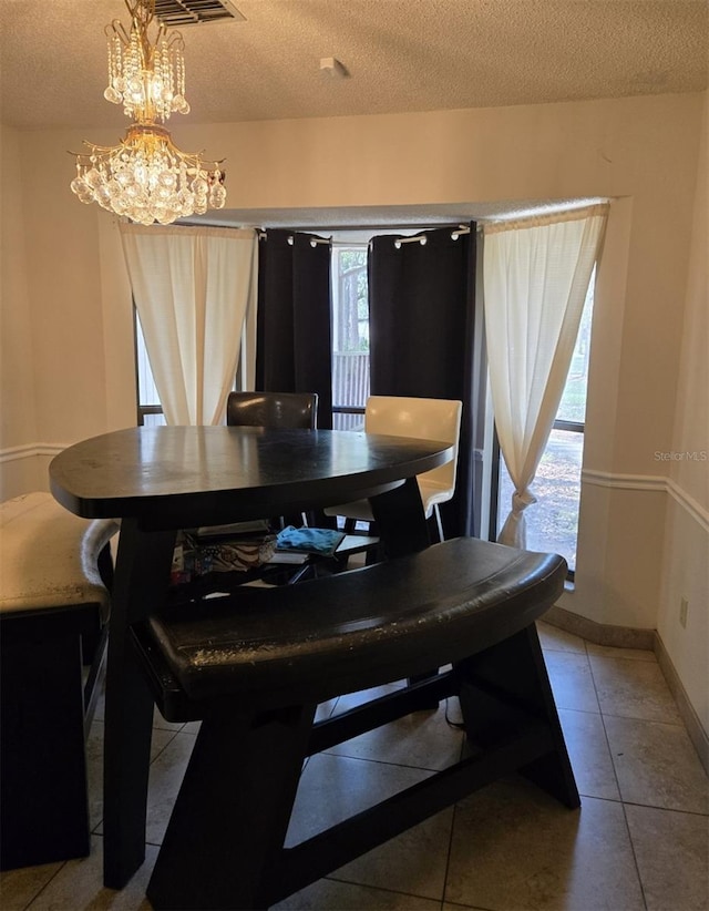 tiled dining space with plenty of natural light, an inviting chandelier, and a textured ceiling