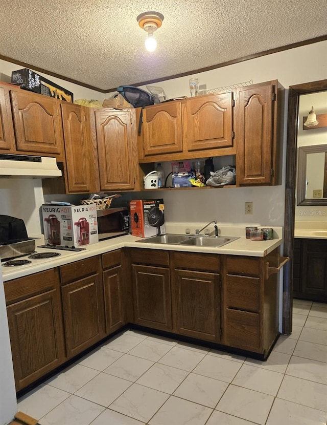 kitchen with stainless steel microwave, a textured ceiling, and under cabinet range hood