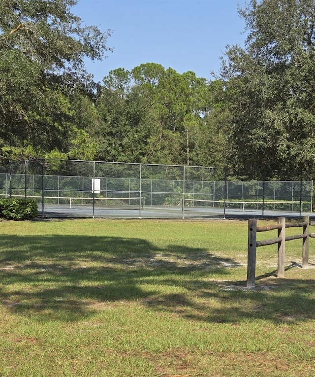 view of home's community featuring fence, a yard, and a tennis court