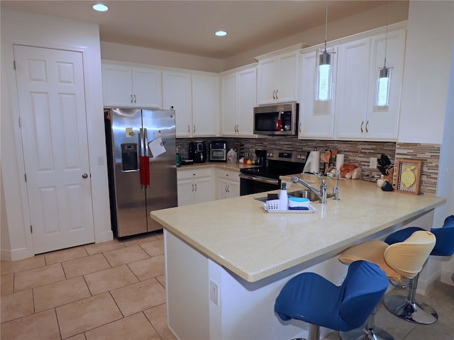 kitchen featuring decorative light fixtures, stainless steel appliances, kitchen peninsula, and white cabinetry