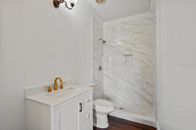 bathroom featuring toilet, a tile shower, vanity, and hardwood / wood-style floors