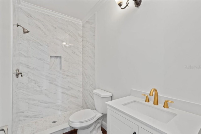 bathroom featuring ornamental molding, toilet, vanity, and tiled shower