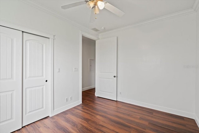 unfurnished bedroom with ornamental molding, ceiling fan, dark wood-type flooring, and a closet