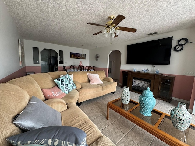 tiled living room featuring ceiling fan and a textured ceiling