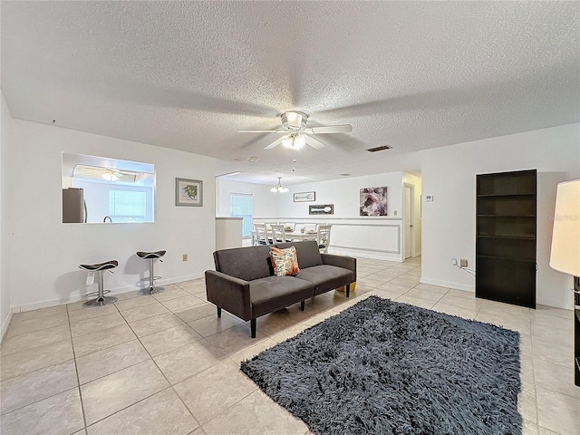 tiled living room with ceiling fan and a textured ceiling