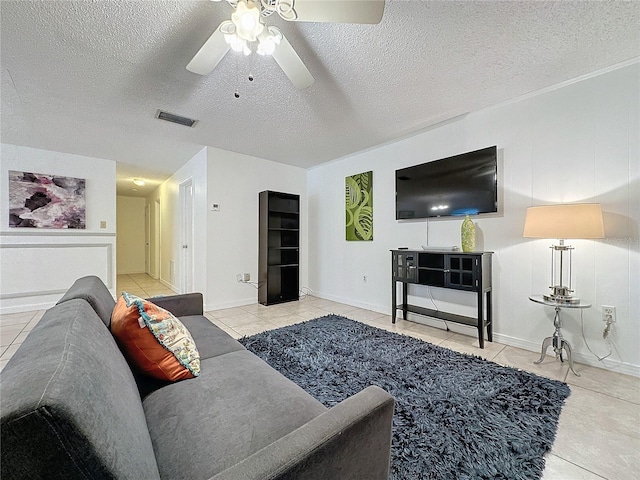 living room featuring ceiling fan, light tile patterned floors, and a textured ceiling