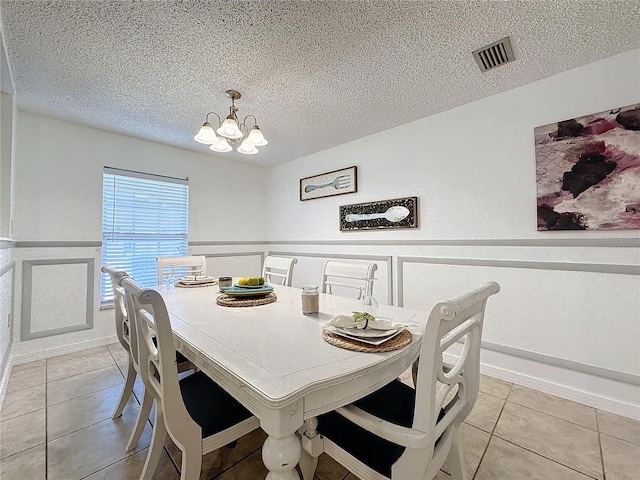 dining area with light tile patterned flooring, a chandelier, and a textured ceiling