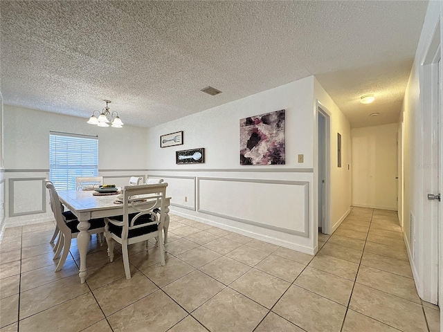 tiled dining space featuring a textured ceiling and a chandelier