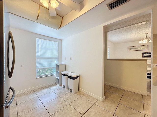 kitchen featuring a textured ceiling, ceiling fan with notable chandelier, stainless steel fridge, and light tile patterned flooring