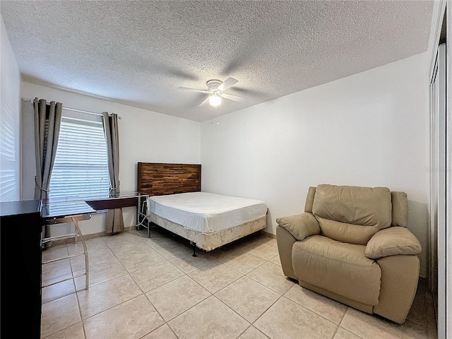 bedroom with ceiling fan, a closet, light tile patterned floors, and a textured ceiling