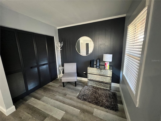 living area featuring crown molding, hardwood / wood-style flooring, and wooden walls