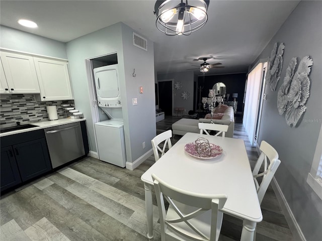 dining area featuring stacked washer and clothes dryer, sink, ceiling fan with notable chandelier, and light hardwood / wood-style floors