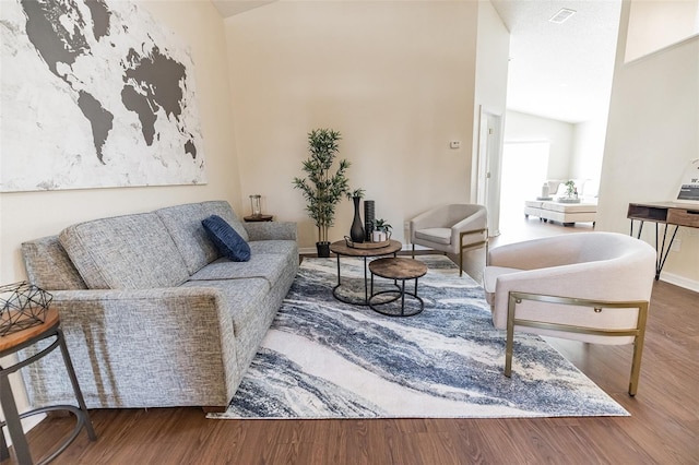 living room with wood-type flooring and high vaulted ceiling