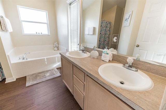 bathroom with tiled tub, wood-type flooring, and vanity