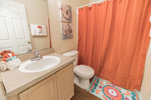 bathroom featuring curtained shower, wood-type flooring, vanity, and toilet