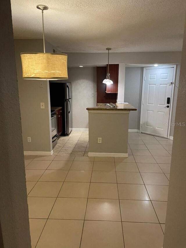 kitchen with light tile patterned floors, a textured ceiling, pendant lighting, and kitchen peninsula