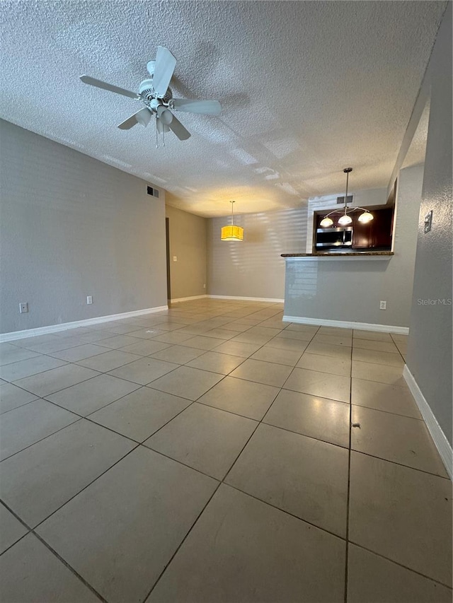 unfurnished living room with ceiling fan, light tile patterned floors, and a textured ceiling