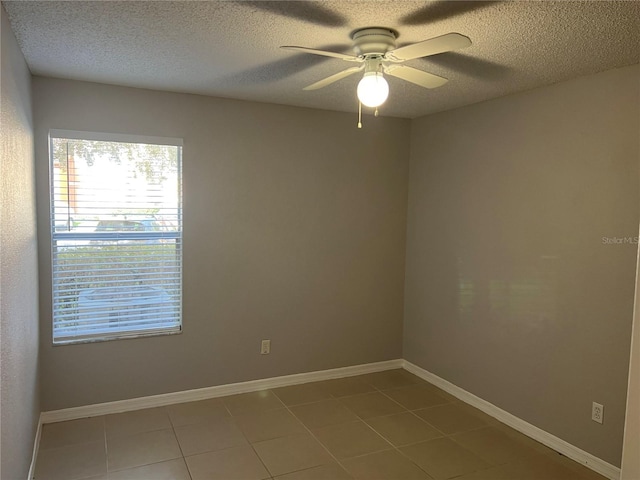 tiled empty room with ceiling fan and a textured ceiling