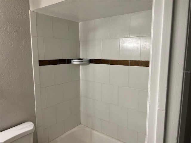 bathroom with toilet and tiled shower / bath combo