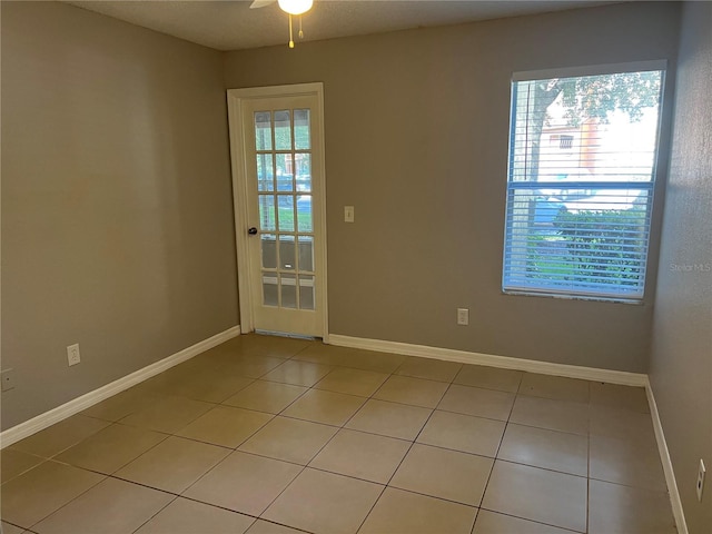 tiled spare room featuring ceiling fan and a healthy amount of sunlight